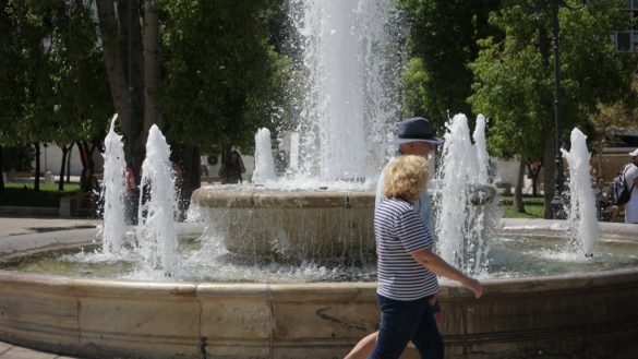 Δύο άνθρωποι περπατούν μπροστά από σιντριβάνι